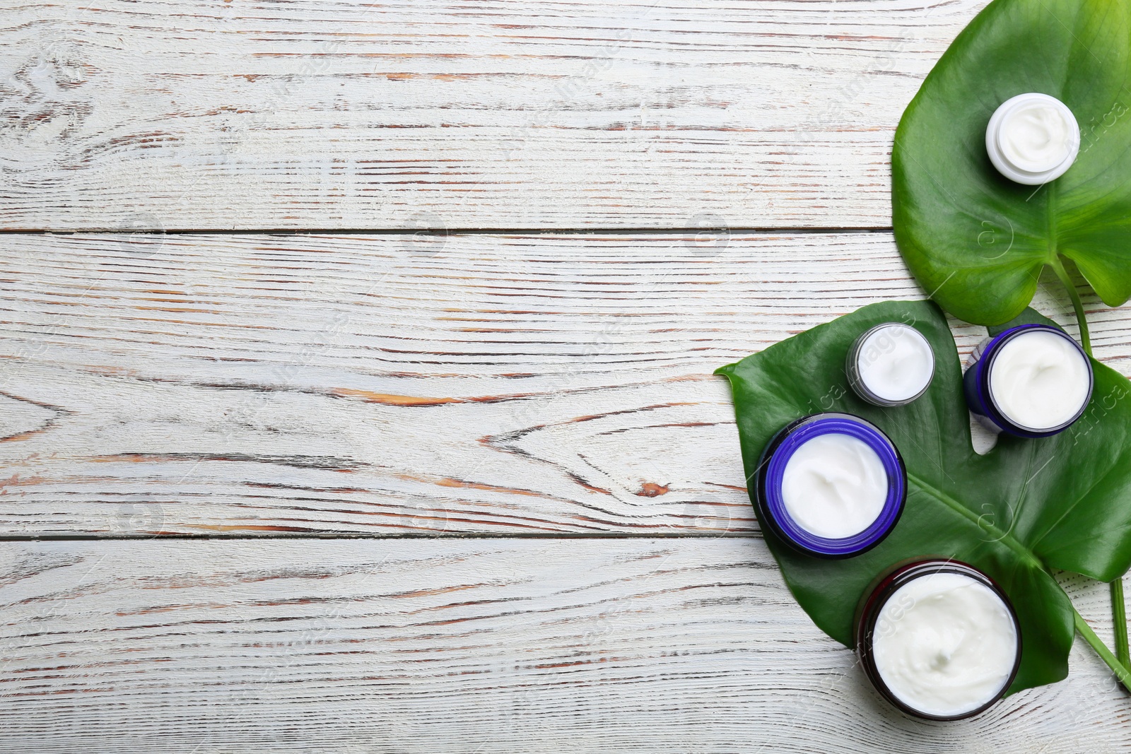 Photo of Jars with different body cream on wooden background