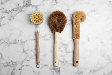 Photo of Cleaning brushes for dish washing on white marble table, flat lay