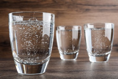 Photo of Glasses of soda water on wooden table, closeup