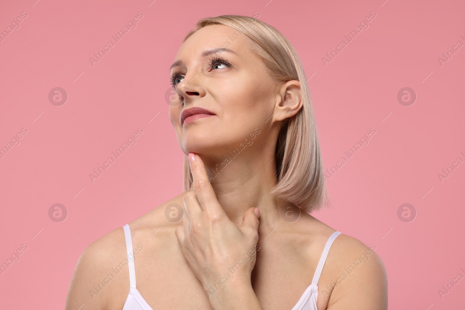 Photo of Beautiful woman touching her neck on pink background