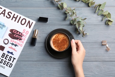 Photo of Young woman with cup of delicious hot coffee at table, top view