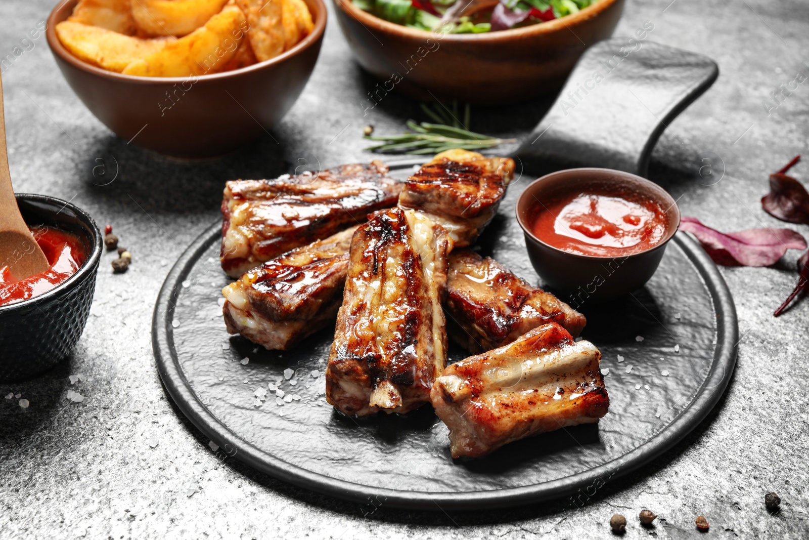 Photo of Board with delicious ribs on grey table