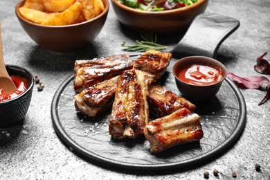 Board with delicious ribs on grey table