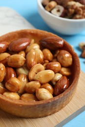 Photo of Tartlets with caramelized nuts on wooden board, closeup. Delicious dessert