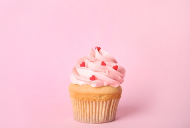 Photo of Tasty cupcake with heart shaped sprinkles for Valentine's Day on pink background