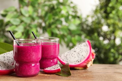 Photo of Delicious pitahaya smoothie and fresh fruits on wooden table, space for text