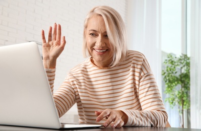 Photo of Mature woman using video chat on laptop at home