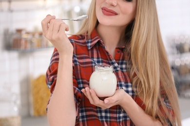 Photo of Young woman with yogurt on blurred background, closeup