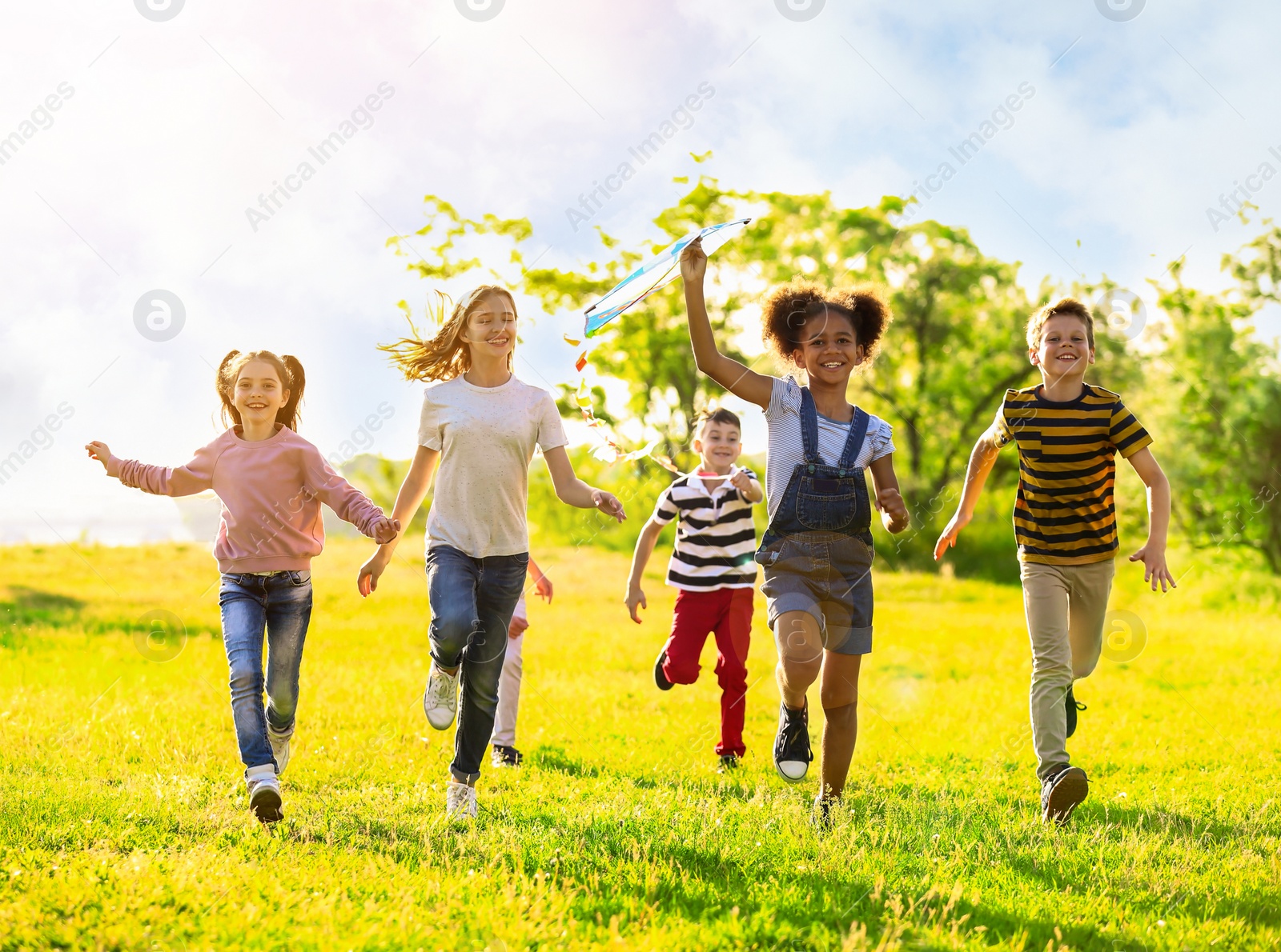 Image of School holidays. Group of happy children playing with kite outdoors 