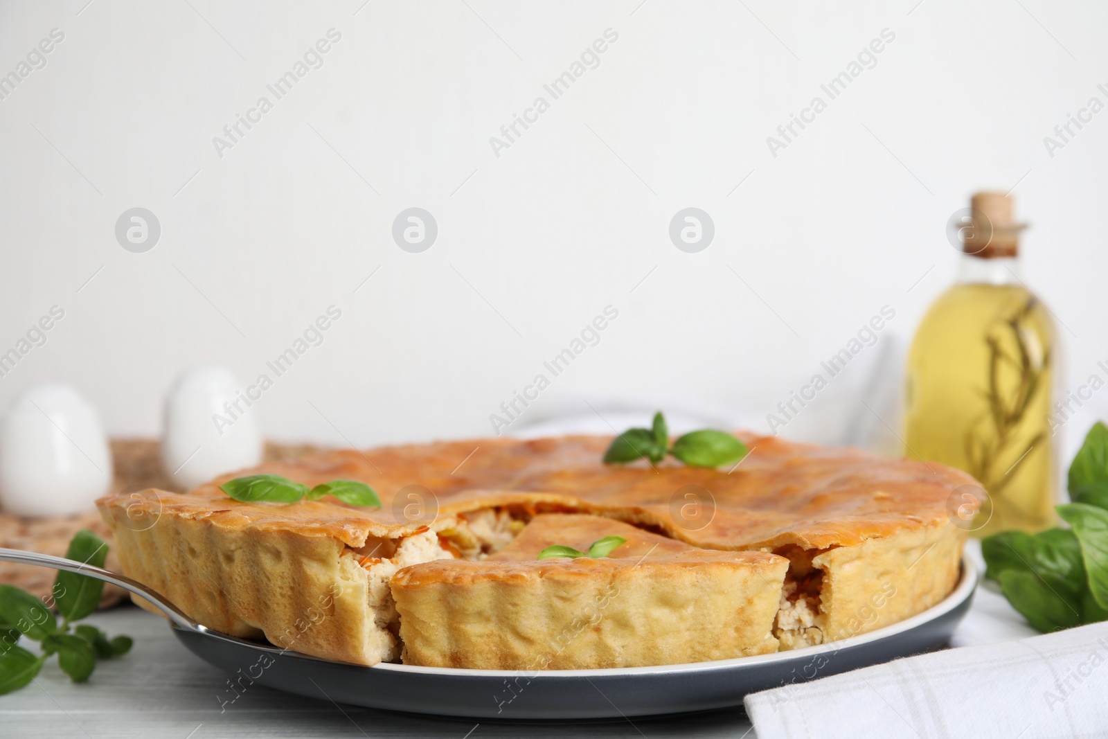 Photo of Delicious meat pie with basil on white table. Space for text