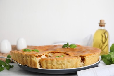 Photo of Delicious meat pie with basil on white table. Space for text