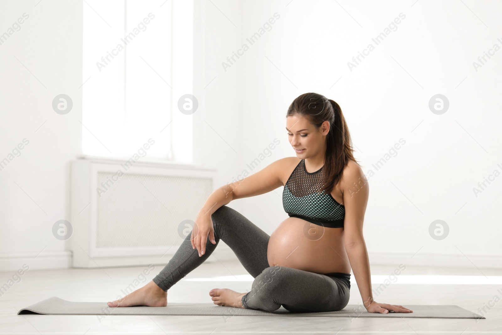 Photo of Young pregnant woman in fitness clothes at home. Space for text