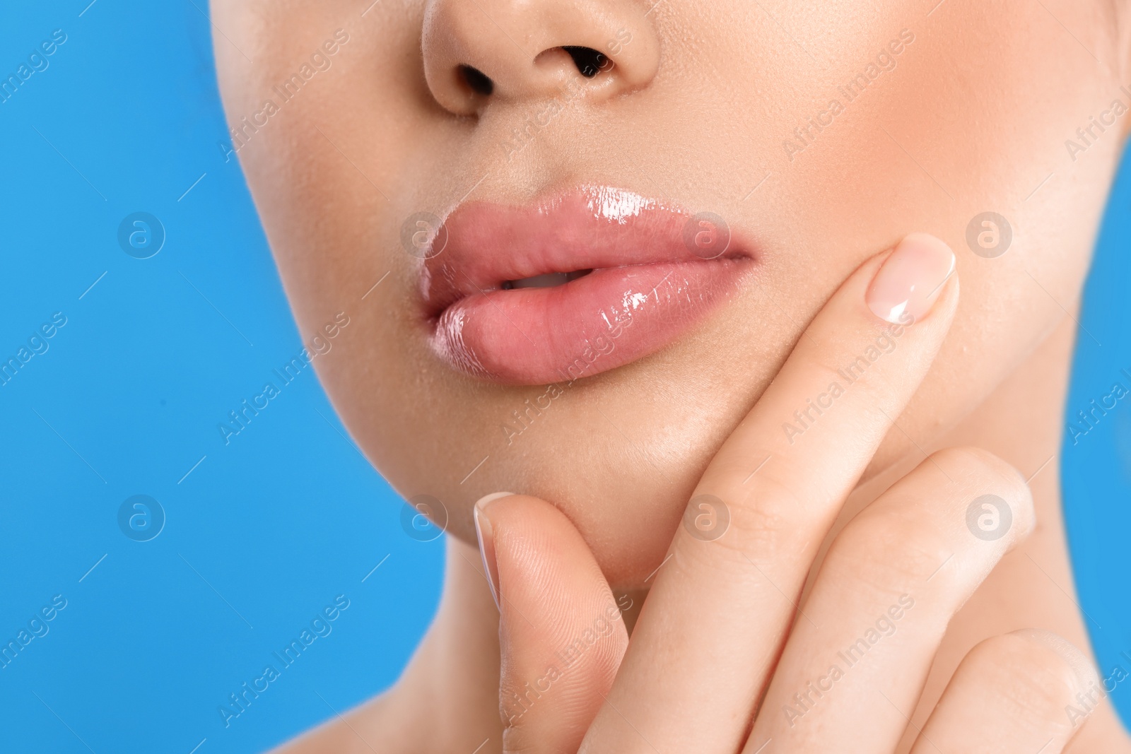 Photo of Young woman with beautiful full lips on light blue background, closeup