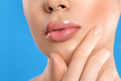 Young woman with beautiful full lips on light blue background, closeup