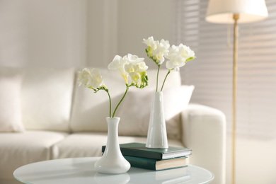 Photo of Beautiful white freesia flowers and books in light room