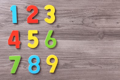 Photo of Colorful numbers on wooden school desk, flat lay. Space for text