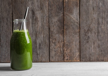 Photo of Bottle with delicious detox juice on table