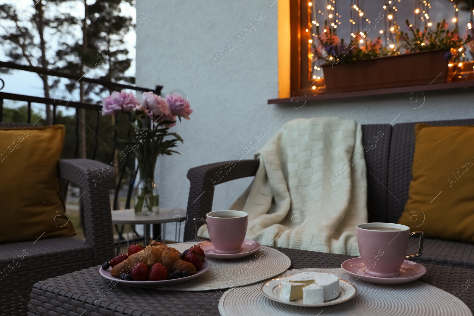 Photo of Rattan table with drink and food on outdoor terrace in evening