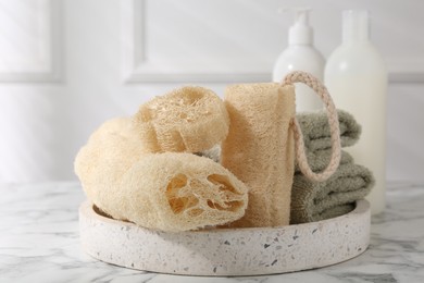 Photo of Loofah sponges, towels, soap and cosmetic products on white marble table
