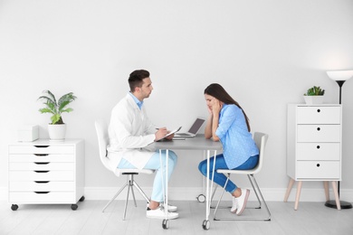 Photo of Depressed young woman having appointment with psychologist in office