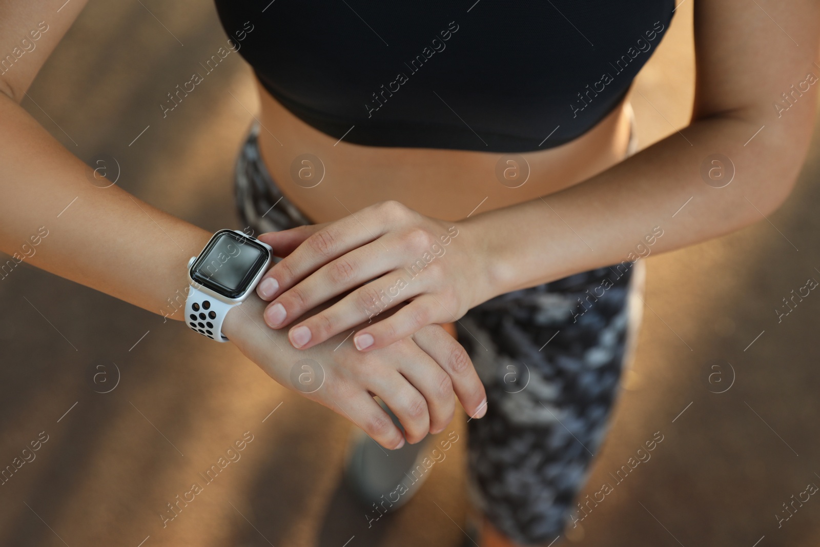 Photo of Woman using modern smart watch during training outdoors, above view