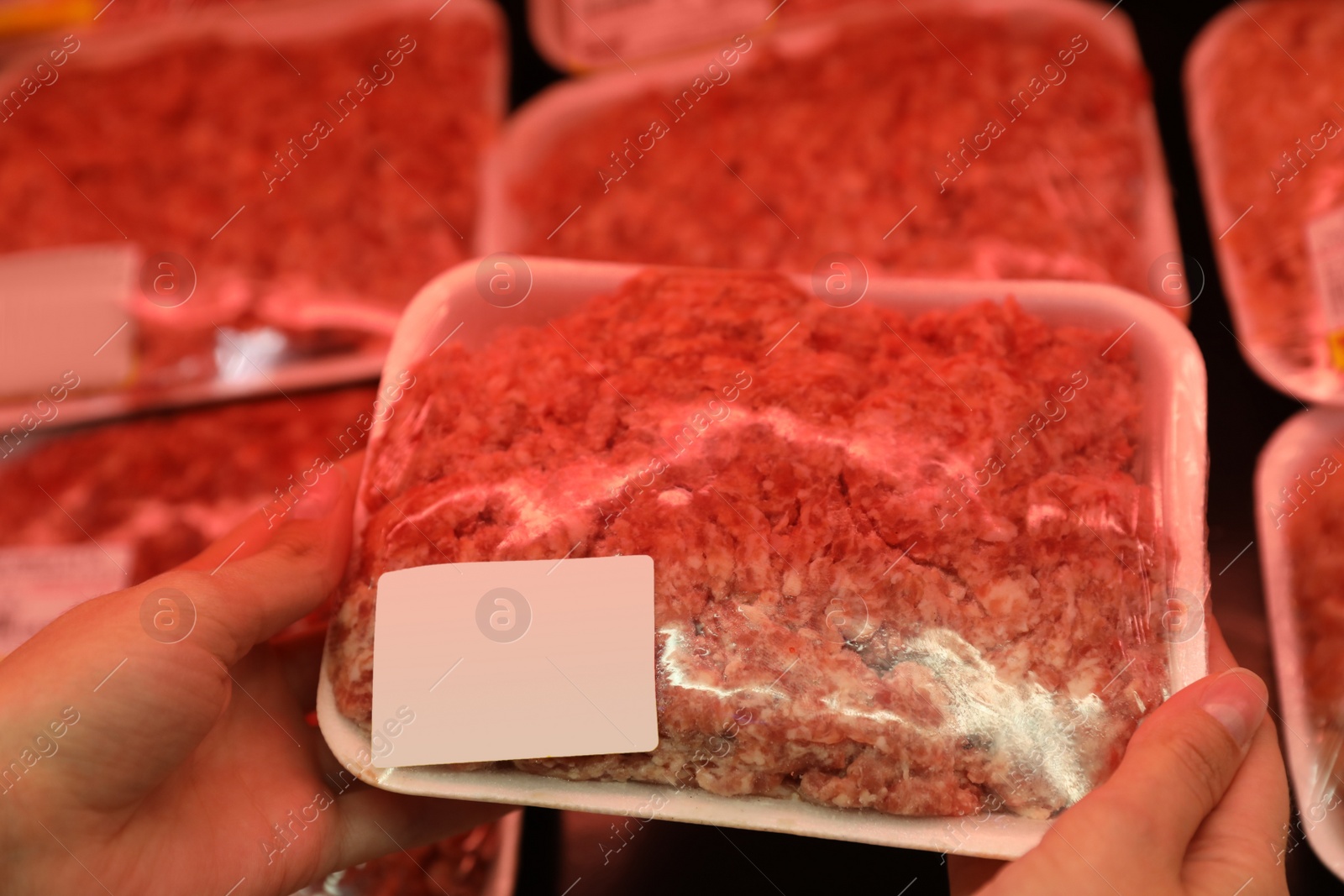 Photo of Woman taking packed forcemeat from shelf in supermarket