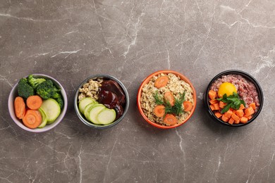 Photo of Natural pet food in feeding bowls on grey table, flat lay