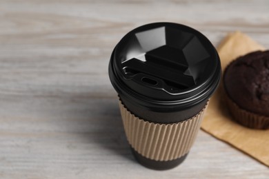 Photo of Paper cup with black lid on wooden table, closeup and space for text. Coffee to go