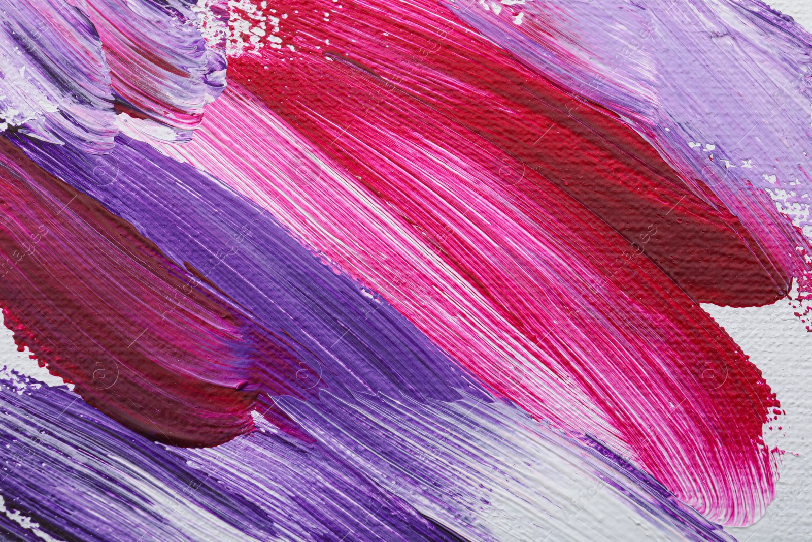 Photo of Strokes of colorful oil paints on white canvas, closeup