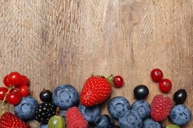 Photo of Different fresh berries on wooden table, flat lay. Space for text