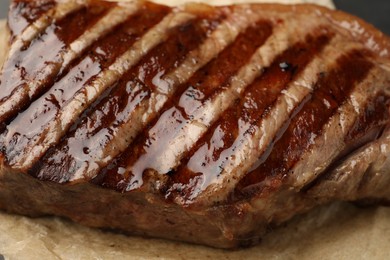 Photo of Delicious grilled beef steak on parchment paper, closeup