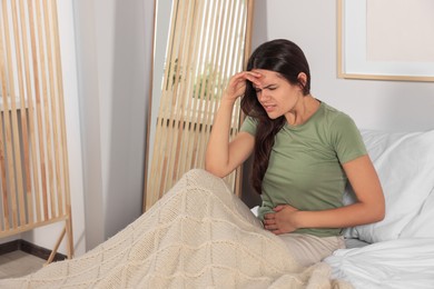 Photo of Young woman suffering from cystitis on bed at home