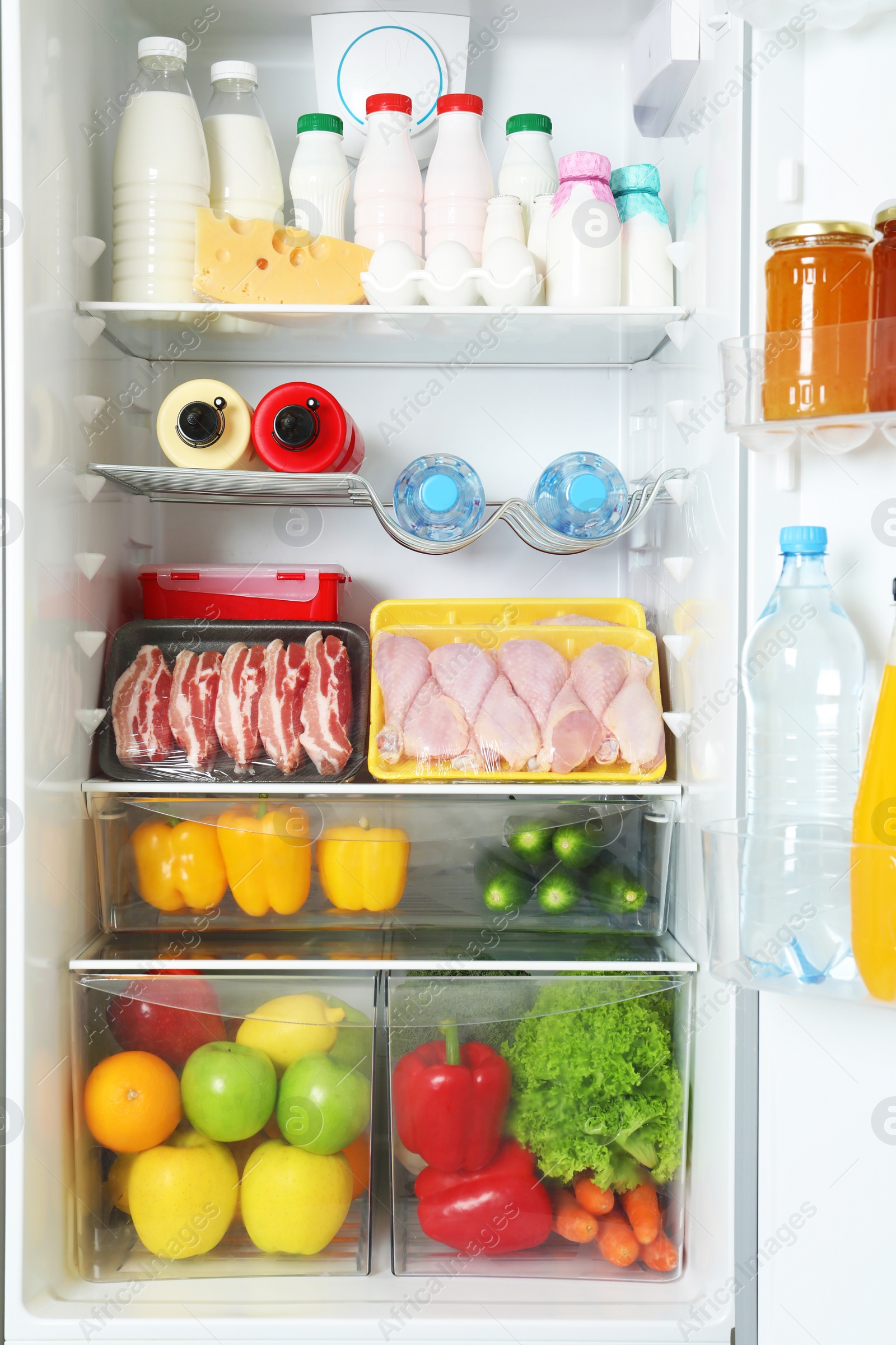 Photo of Open refrigerator with many different products, closeup