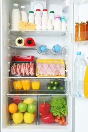 Photo of Open refrigerator with many different products, closeup