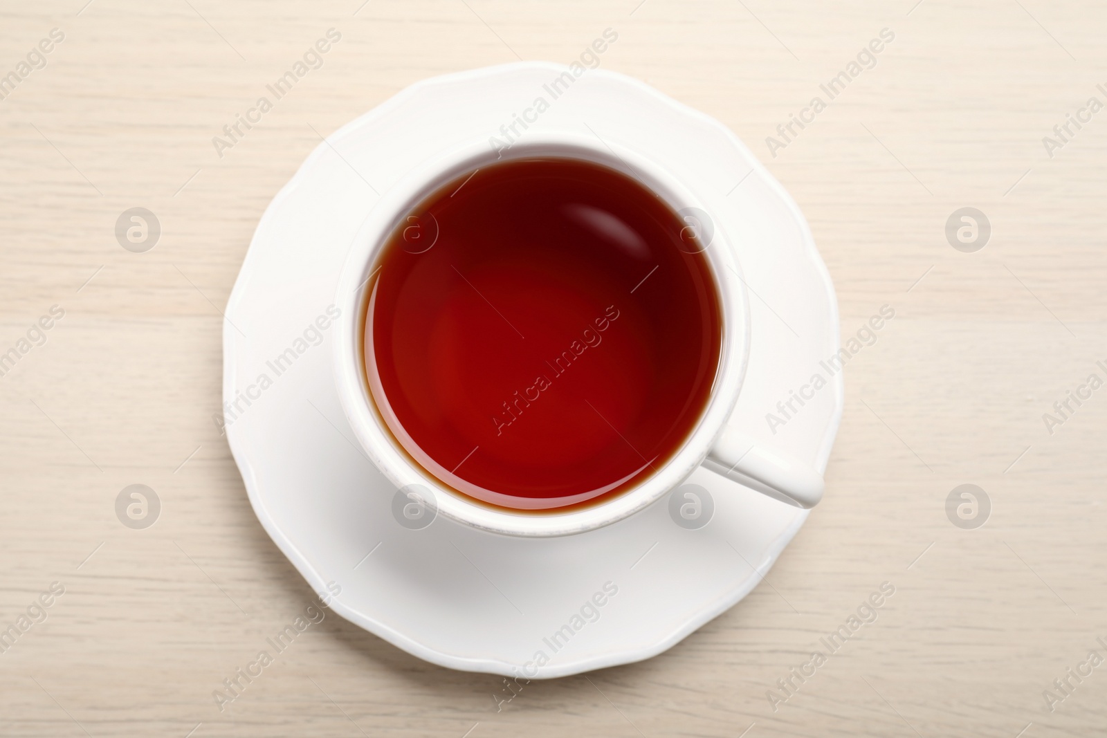 Photo of Freshly brewed rooibos tea in ceramic cup on wooden table, top view