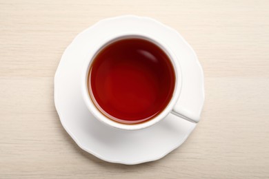 Photo of Freshly brewed rooibos tea in ceramic cup on wooden table, top view