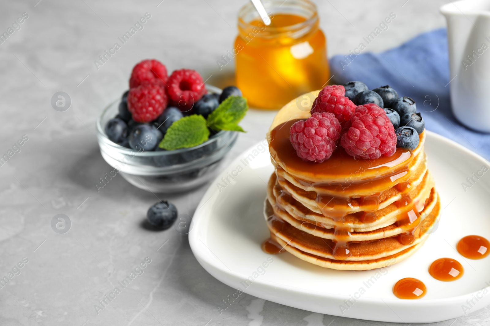 Photo of Delicious pancakes with fresh berries and syrup on grey table