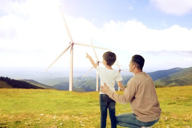 Father with son looking at wind energy turbines
