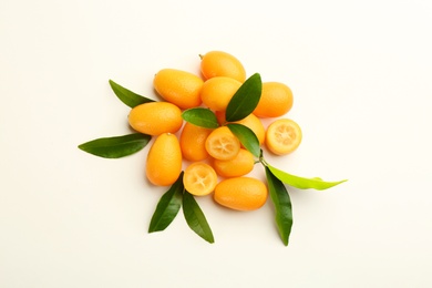 Fresh ripe kumquats with green leaves on white background, flat lay
