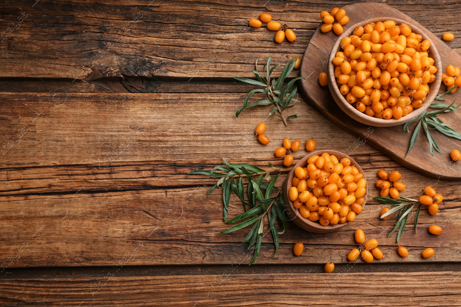 Photo of Fresh ripe sea buckthorn on wooden table, flat lay. Space for text