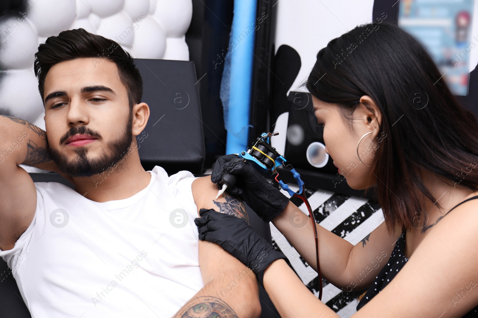 Photo of Professional artist making tattoo with machine in salon