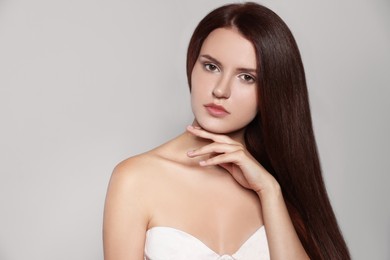 Photo of Portrait of beautiful young woman with healthy strong hair on light gray background