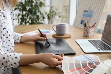 Photo of Professional designer with graphic tablet at wooden table, closeup