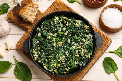 Photo of Tasty spinach dip with eggs in dish served on light wooden table, flat lay