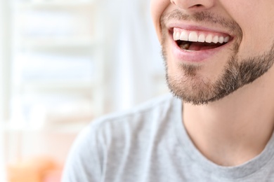 Photo of Young man with beautiful smile indoors. Teeth whitening