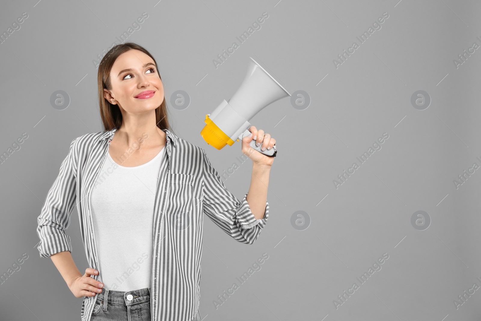 Photo of Young woman with megaphone on light grey background. Space for text