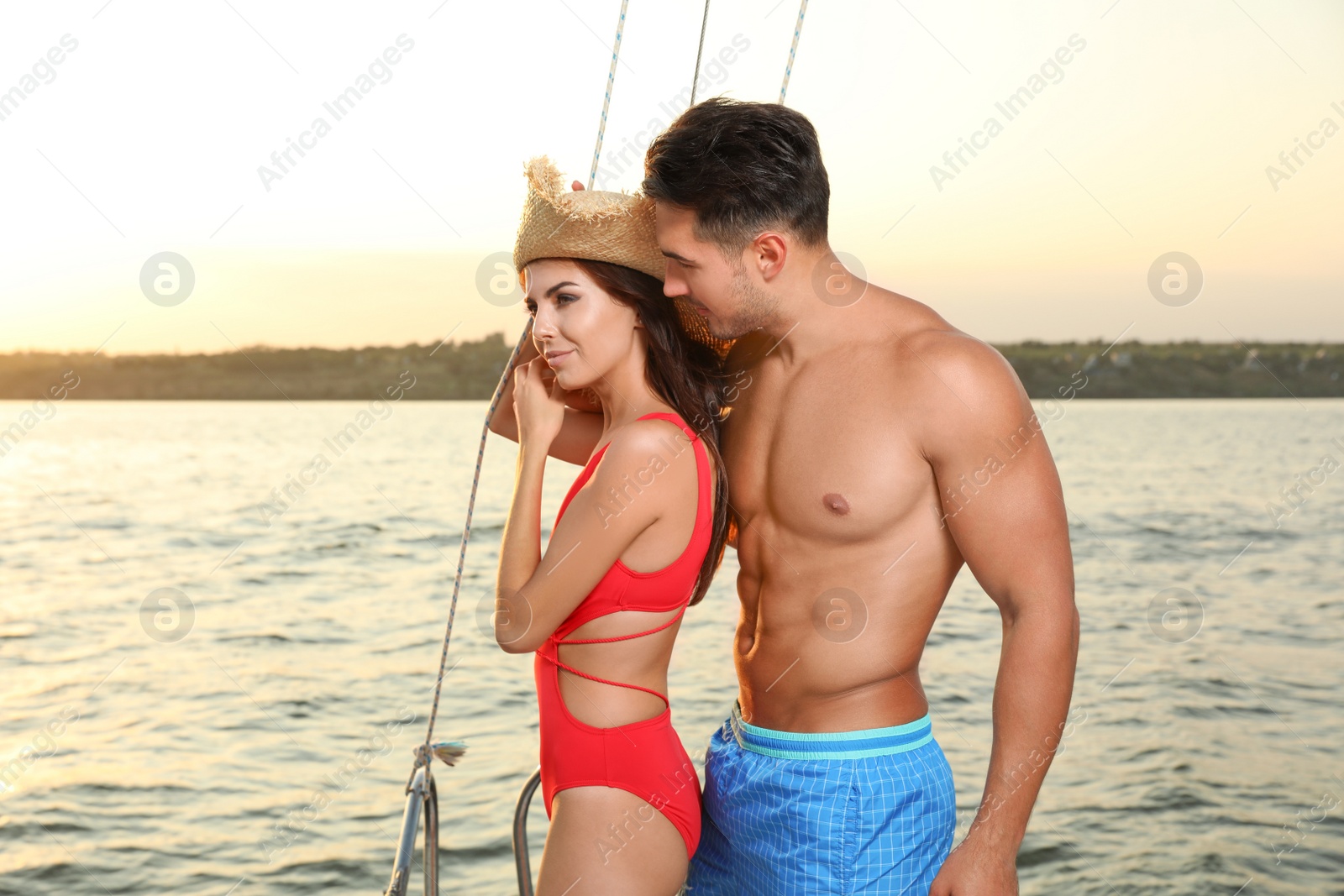 Photo of Young man and his beautiful girlfriend in bikini on yacht. Happy couple during sea trip