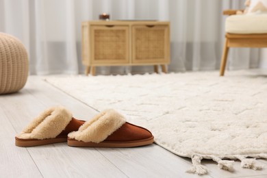 Slippers near soft white carpet in living room. Space for text