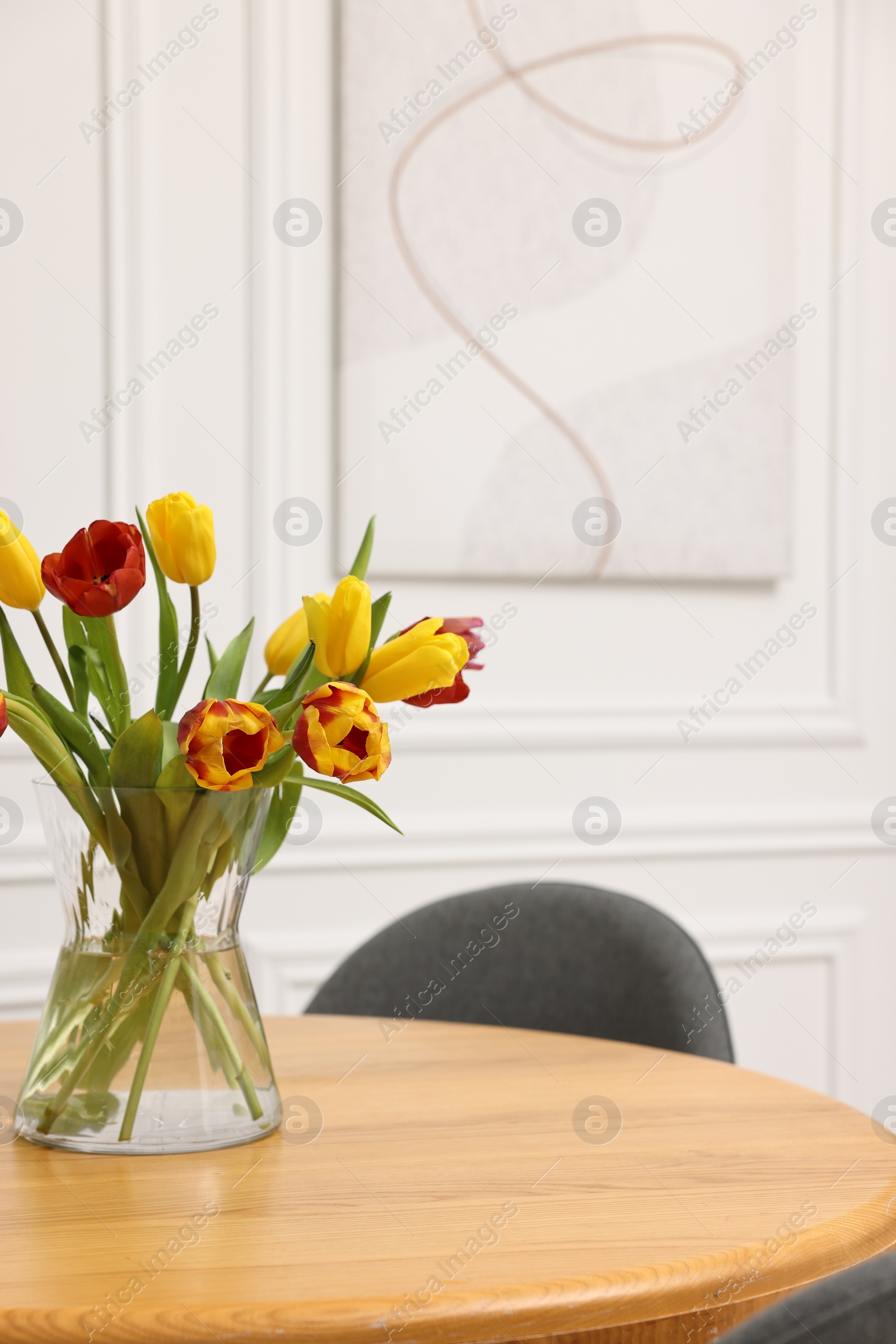 Photo of Vase with beautiful tulips on table in dining room