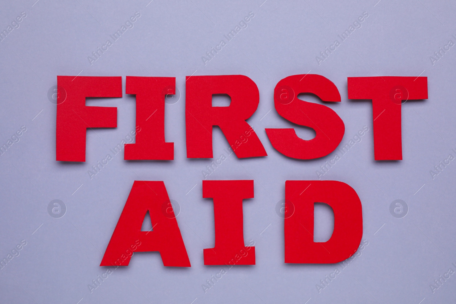Photo of Words First Aid made of red letters on grey background, flat lay